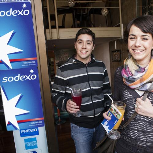 Deux jeunes personnes à coté d'une pancarte Sodexo